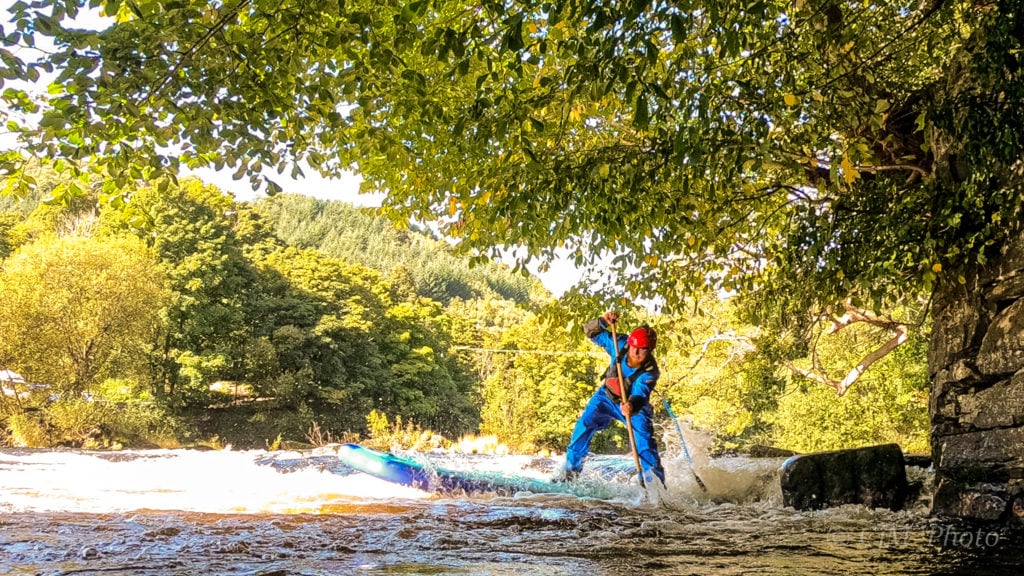 a man standing on a SUP, on a white water river