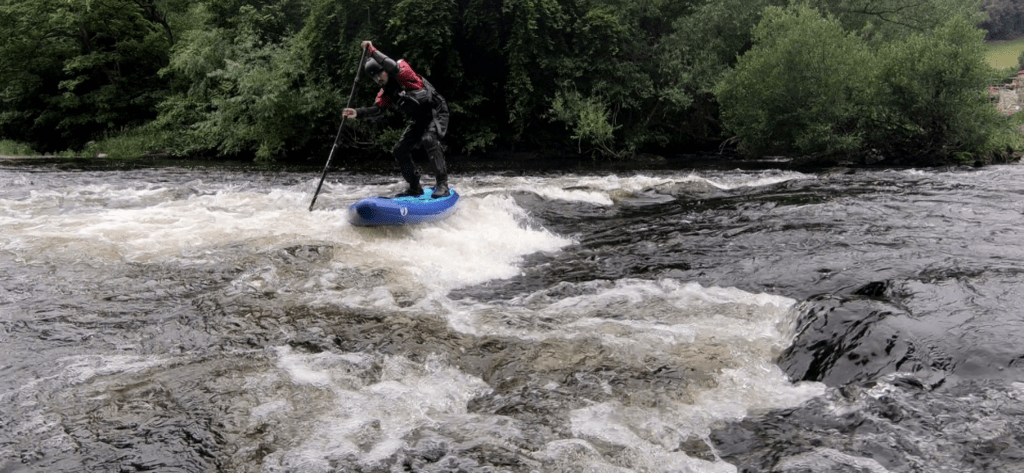 a man on a stand up paddleboard on a white water river