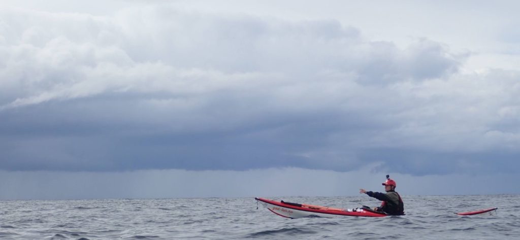 A man in a sea kayak on the sea, pointing