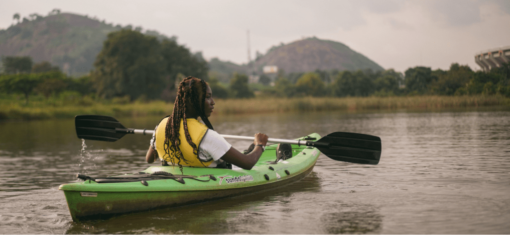 a woman sitting on a calm river on a sit on top kayak