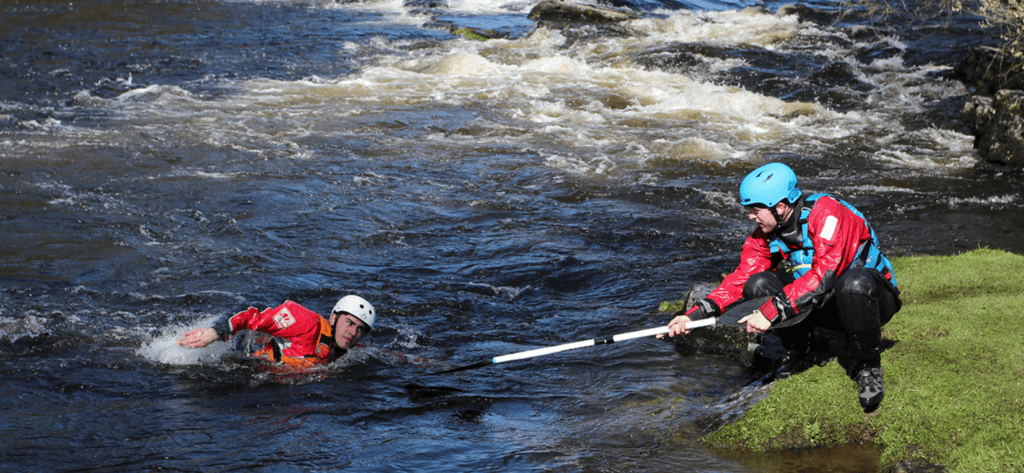 a man in white water being rescued by a man on the bank