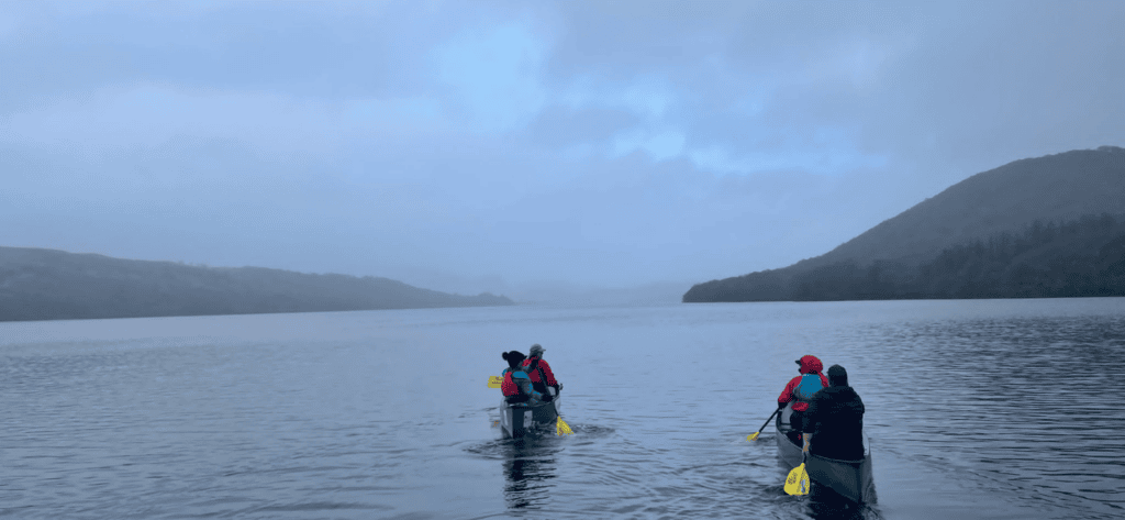 a group in canoes on a misty lake