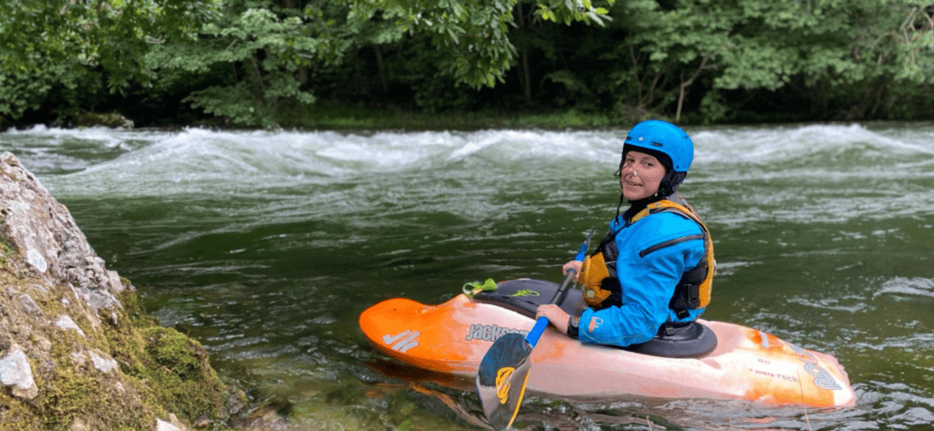 a lady in a freestyle boat about to go down some white water