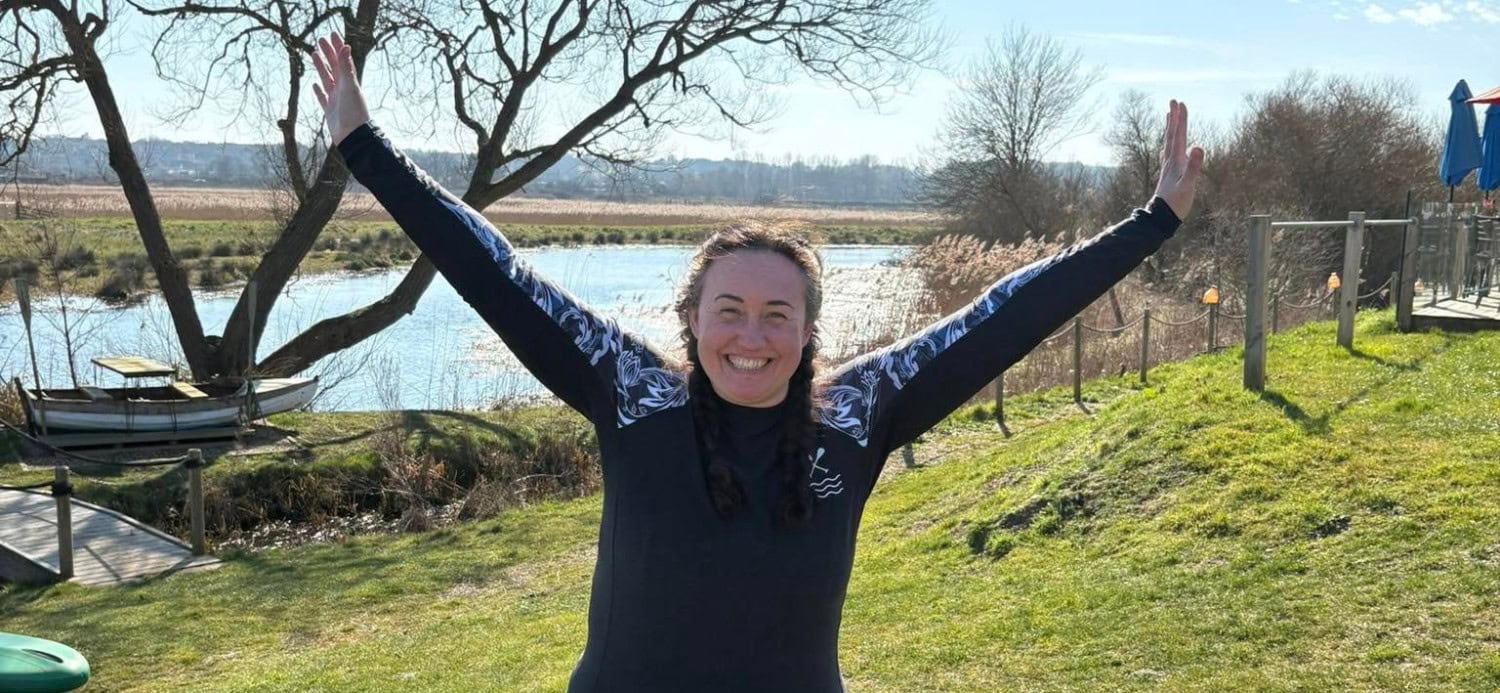 Natahsa with her arms in the air, smiling by the side of the river